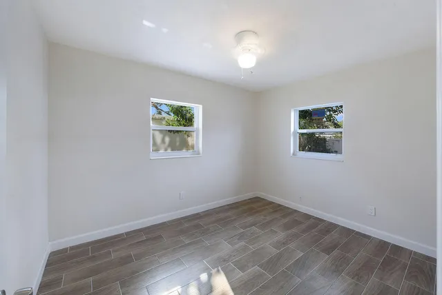an empty room with wooden floor and window