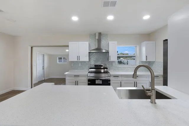 a kitchen with stainless steel appliances granite countertop a sink a stove a refrigerator cabinets and a dining table