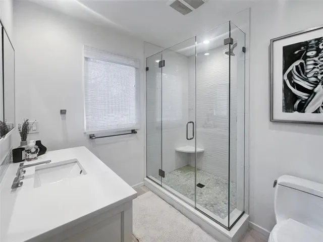 a bathroom with a shower sink mirror and toilet