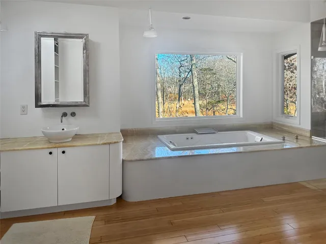 a bathroom with a tub sink and mirror