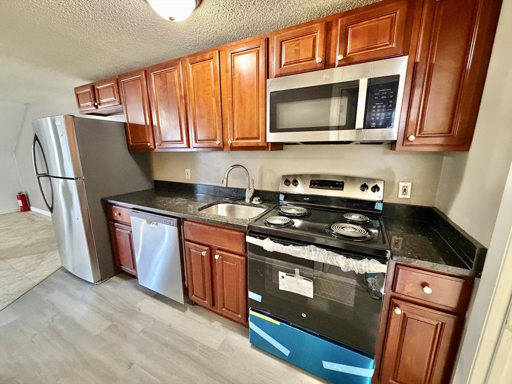 379 Meridian Street, Unit 101 Boston, MA 02128 - Photo 2 of 10 a kitchen with stainless steel appliances granite countertop a stove a sink and a microwave