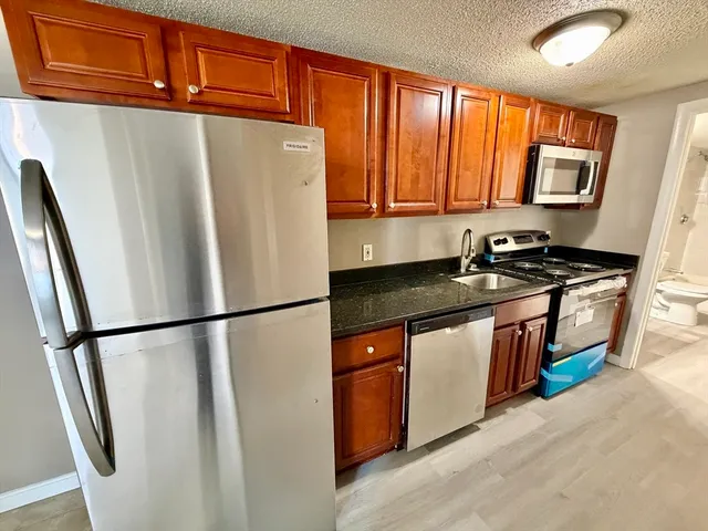 a kitchen with stainless steel appliances granite countertop a refrigerator a sink and a stove