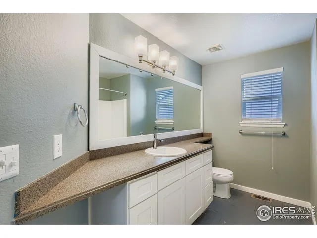 a bathroom with a granite countertop sink a toilet and a mirror