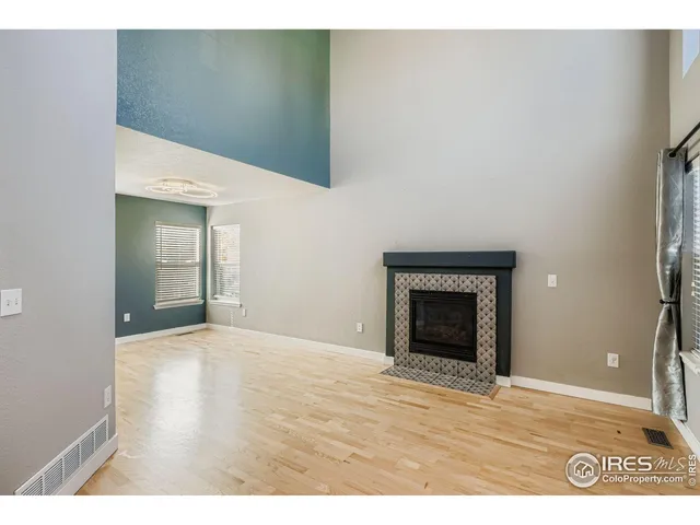 a view of an empty room with wooden floor and a fireplace