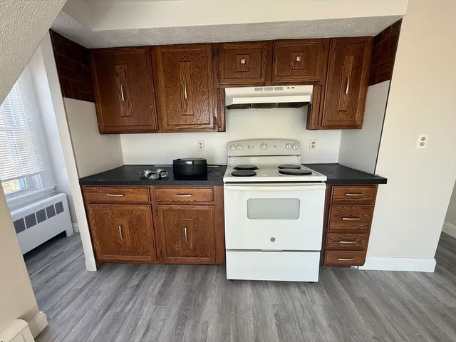 a kitchen with granite countertop wooden cabinets and white appliances
