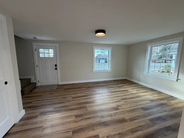 a view of an empty room with window and wooden floor