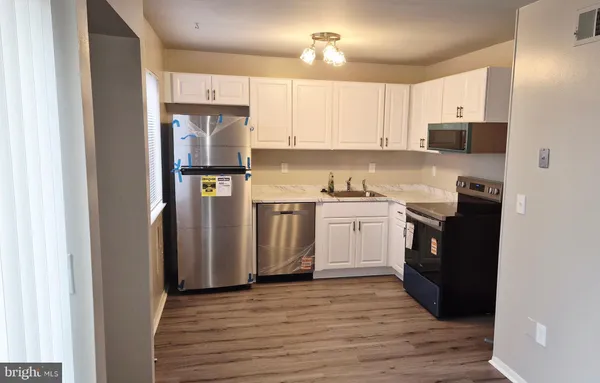 a kitchen with a refrigerator a stove top oven a sink and dishwasher with wooden floor