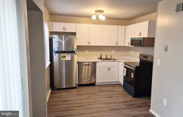 a kitchen with a refrigerator a stove top oven a sink and dishwasher with wooden floor