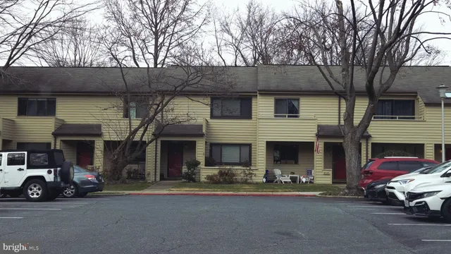a front view of a house with lot of cars and trees