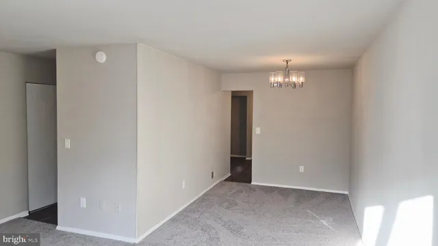 an empty room with a chandelier fan and closet area
