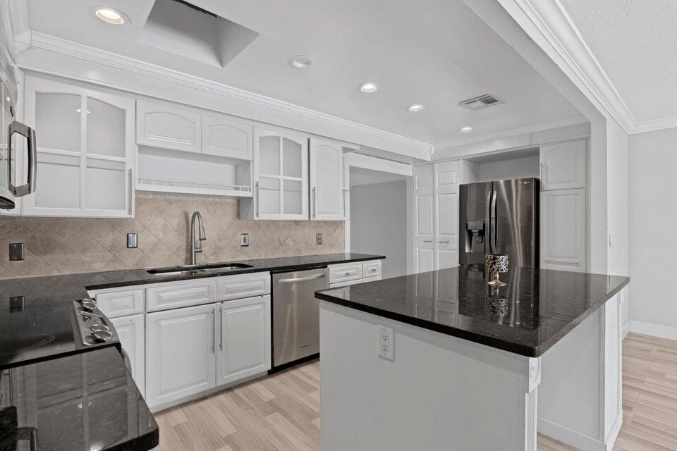 a kitchen with stainless steel appliances granite countertop a sink and white cabinets
