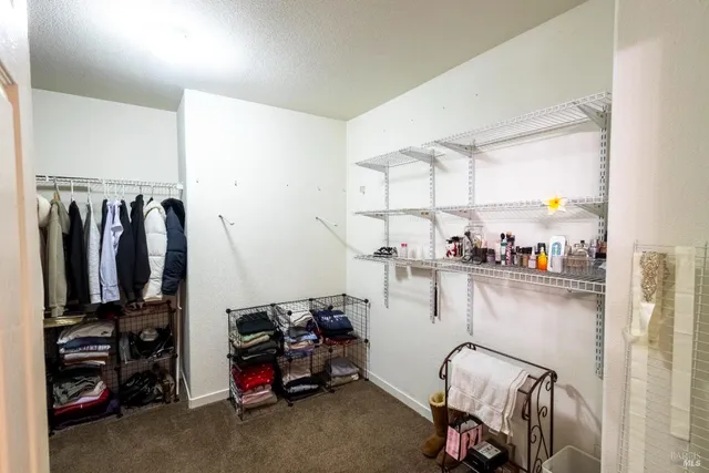a view of walk in closet with clothes and shoes