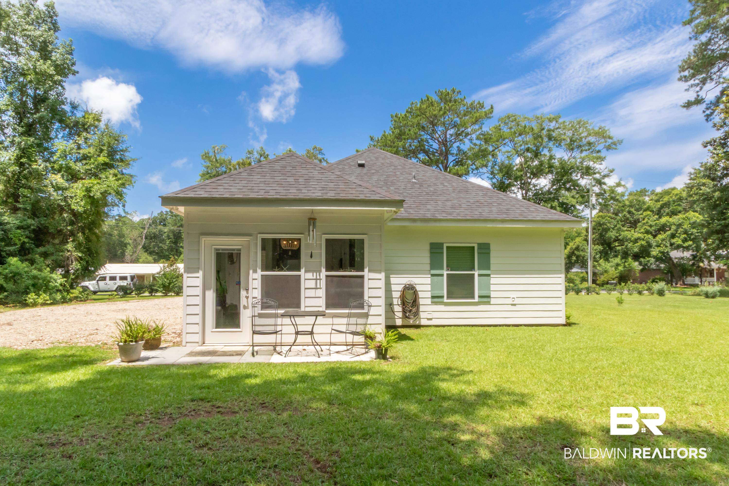 7472 Coopers Landing Road Foley, AL 36535 - Photo 32 of 40 Rear exterior featuring light-colored siding, a dark shingle roof, and a green shuttered window