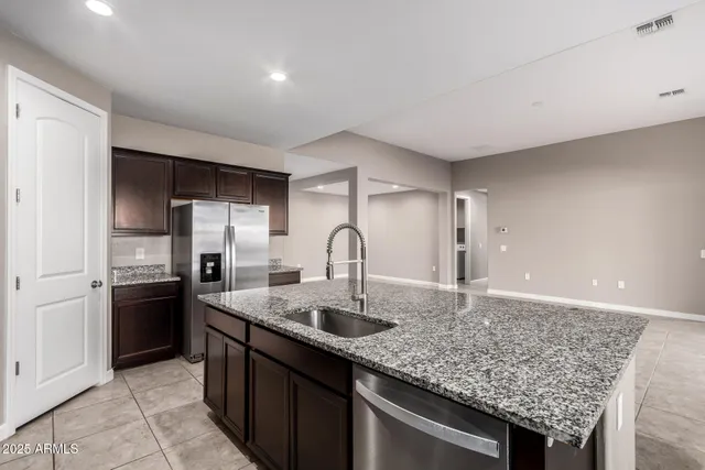a kitchen with stainless steel appliances granite countertop a sink refrigerator and cabinets