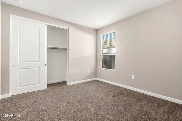 a view of an empty room with closet and a window