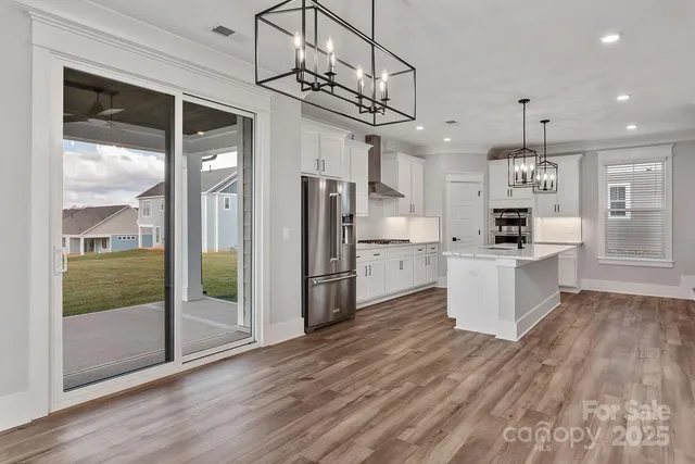 a kitchen with stainless steel appliances kitchen island granite countertop a refrigerator a oven a cabinets and wooden floor