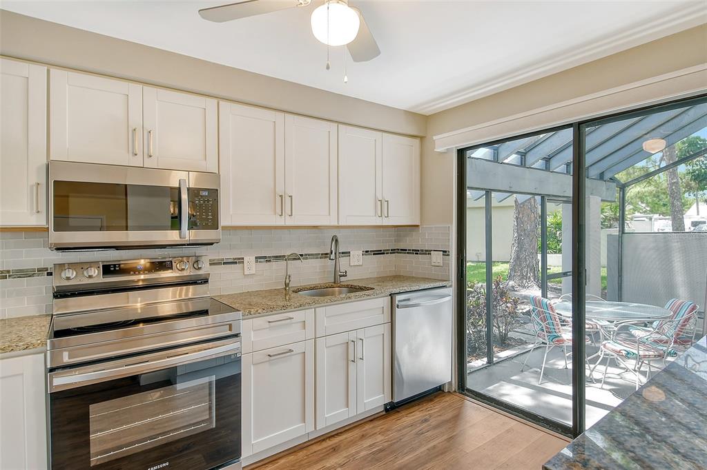2517 Glebe Farm Close, Unit H2 Sarasota, FL 34235 - Photo 11 of 59 a kitchen with stainless steel appliances white cabinets and wooden floor