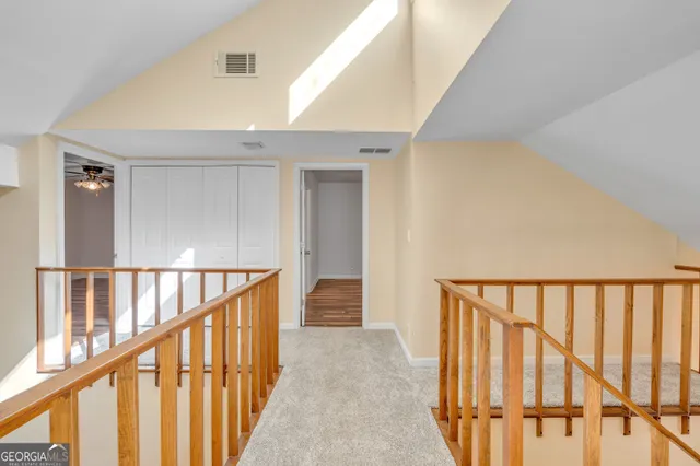 a view of an empty room with wooden floor and a ceiling fan