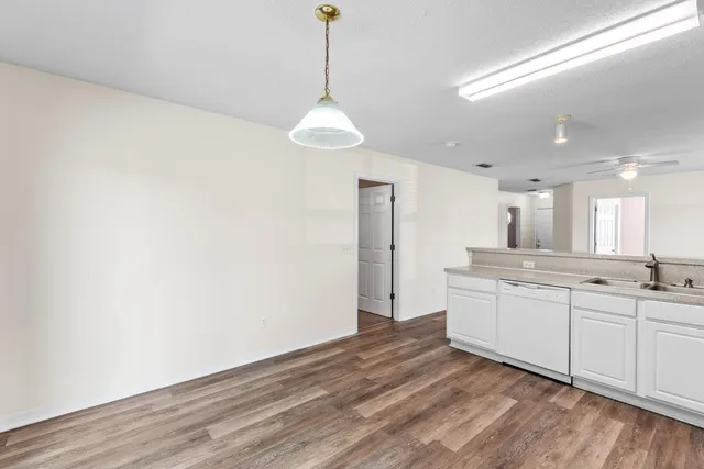 a kitchen with granite countertop a sink cabinets and wooden floor
