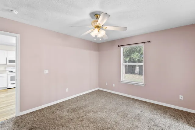 an empty room with a window and a fan