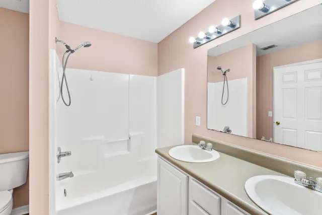 a bathroom with a granite countertop sink tub shower and a mirror