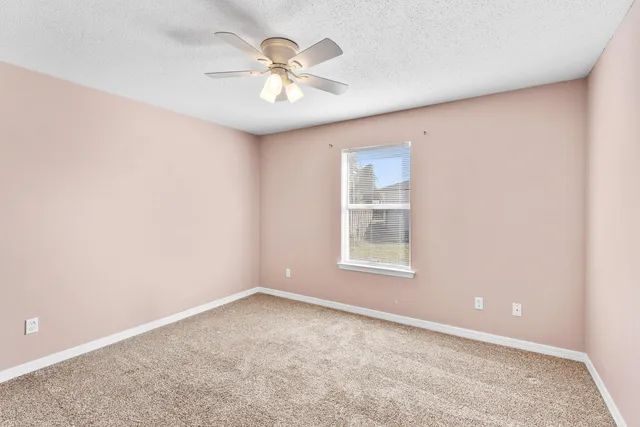 an empty room with a chandelier fan and windows