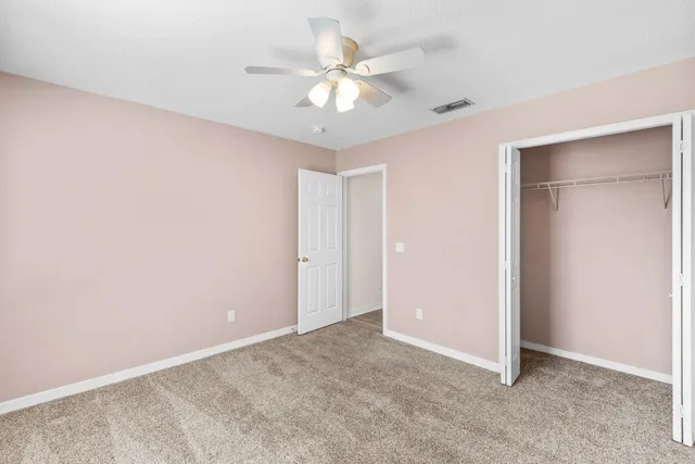an empty room with a chandelier fan and windows