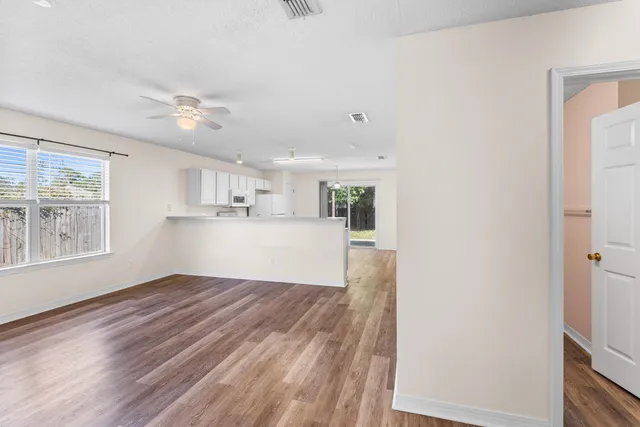 a view of kitchen and empty room with wooden floor and windows
