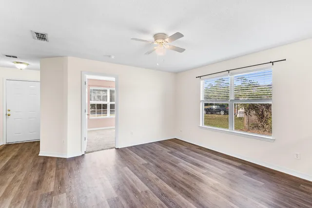 a view of an empty room with wooden floor and a window