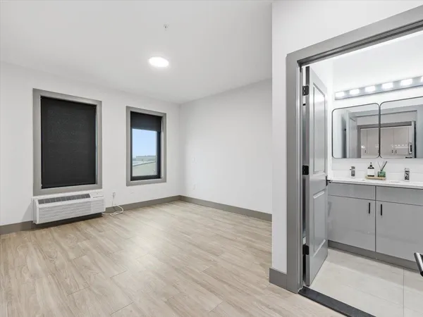 a view of an empty room with cabinet and mirror