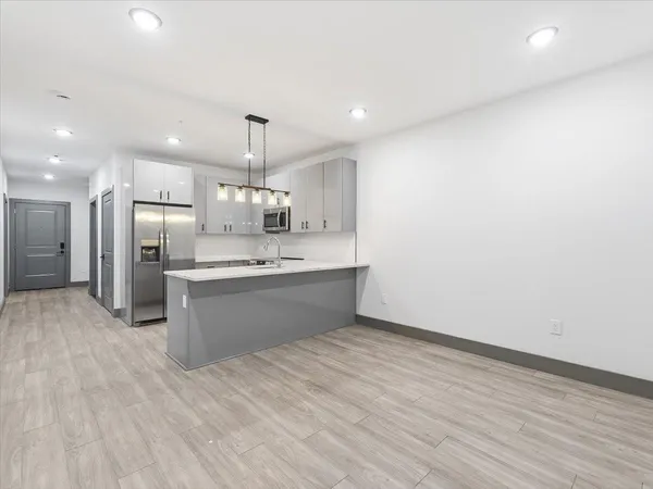 a large kitchen with stainless steel appliances a large kitchen island a hardwood floor and a sink
