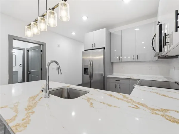 a kitchen with stainless steel appliances a sink dishwasher a refrigerator and cabinets