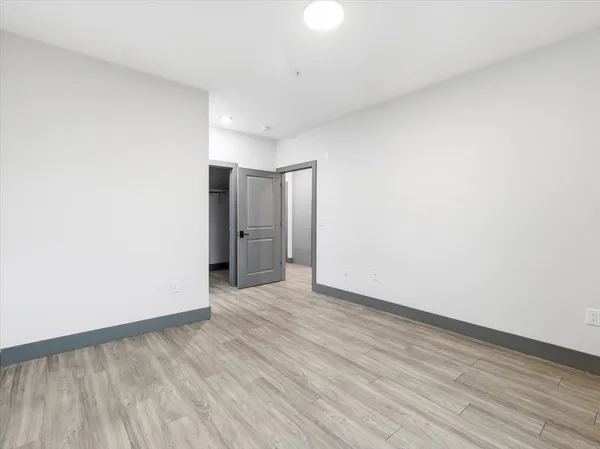 a view of an empty room with wooden floor and closet