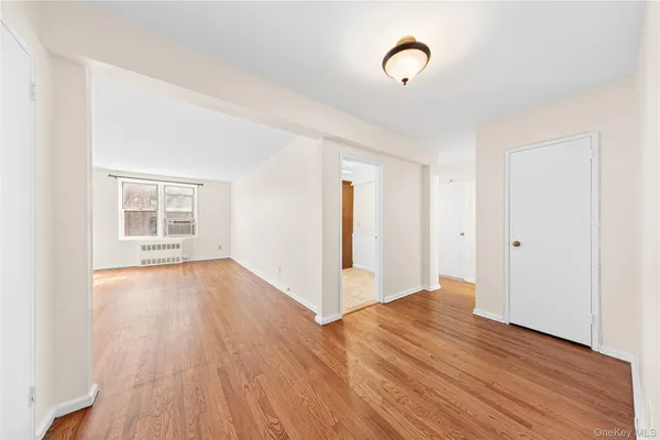 a view of an empty room with wooden floor and window