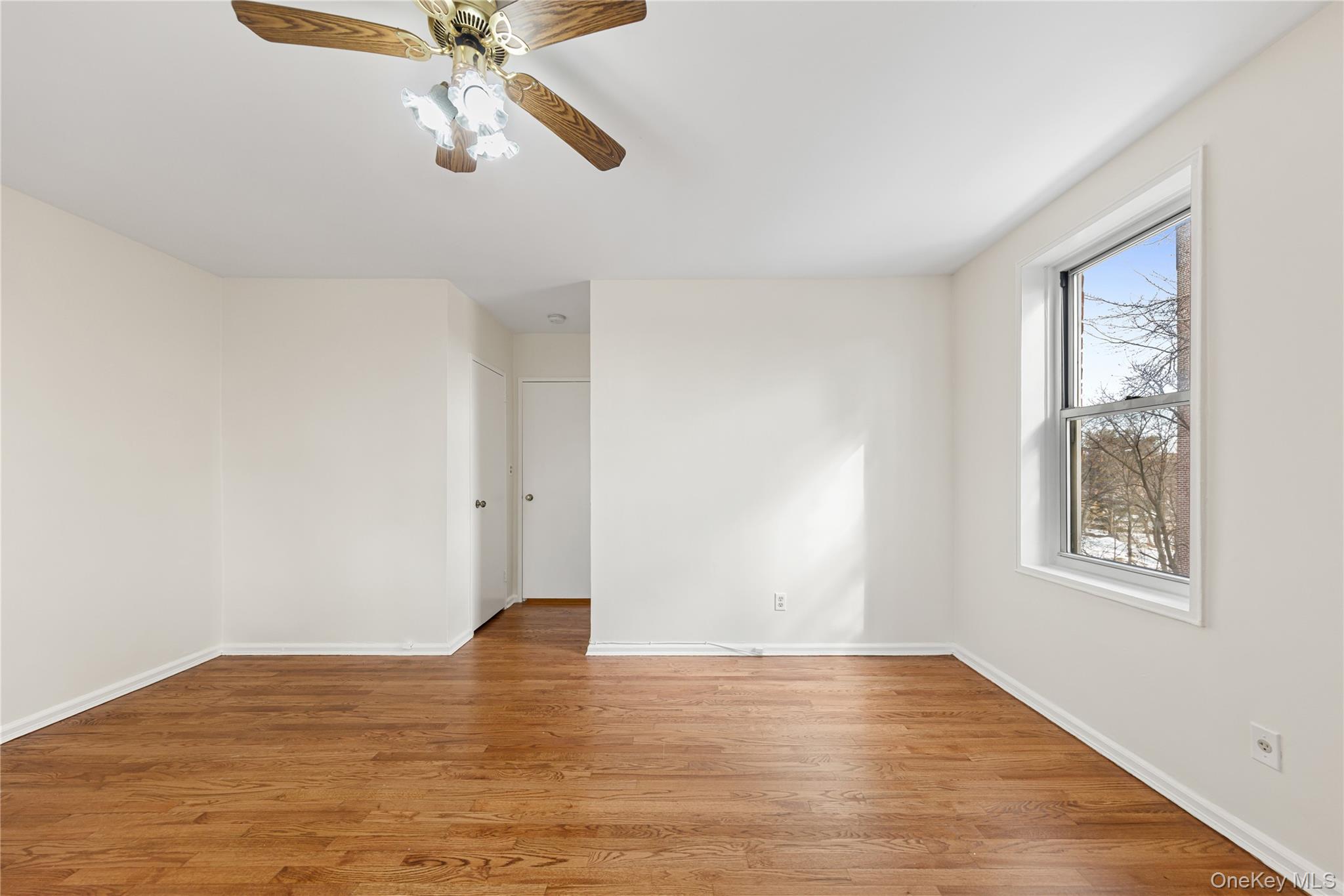 126 Church Street, Unit 2D New Rochelle, NY 10805 - Photo 13 of 32 a view of an empty room with wooden floor and a window