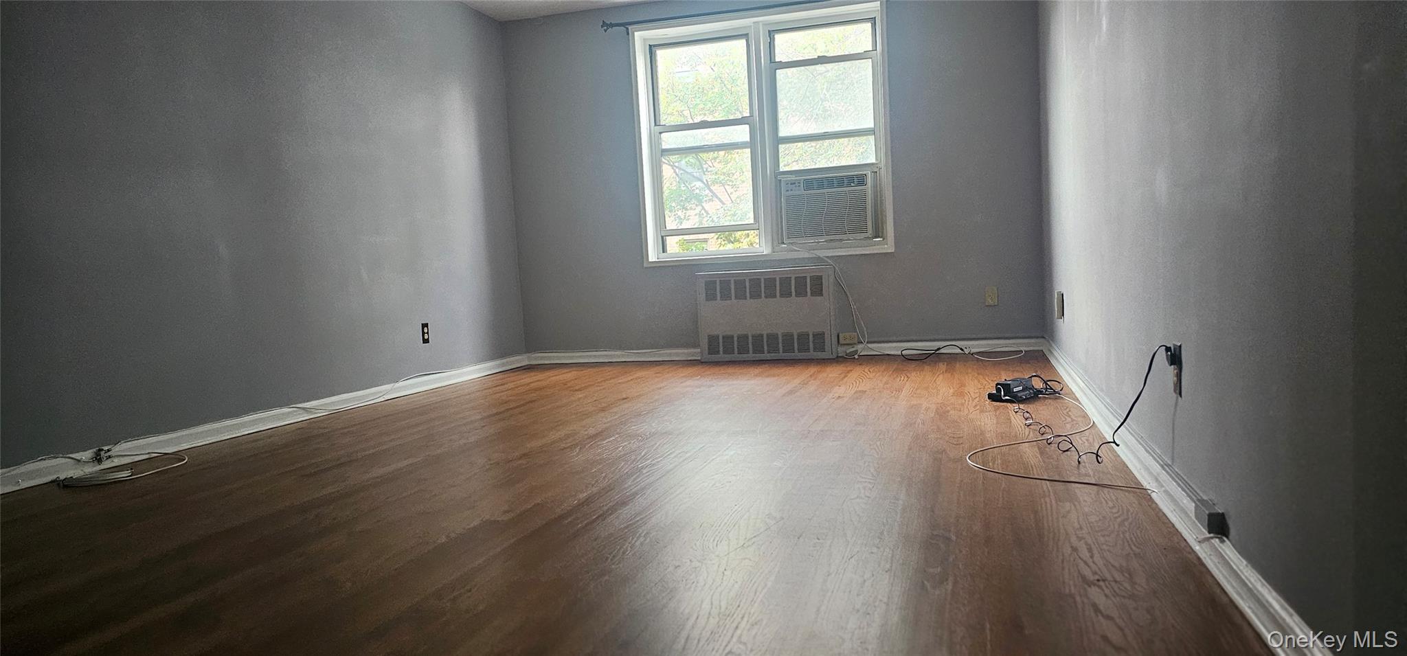 126 Church Street, Unit 2D New Rochelle, NY 10805 - Photo 4 of 15 Empty room featuring wood finished floors and radiator heating unit