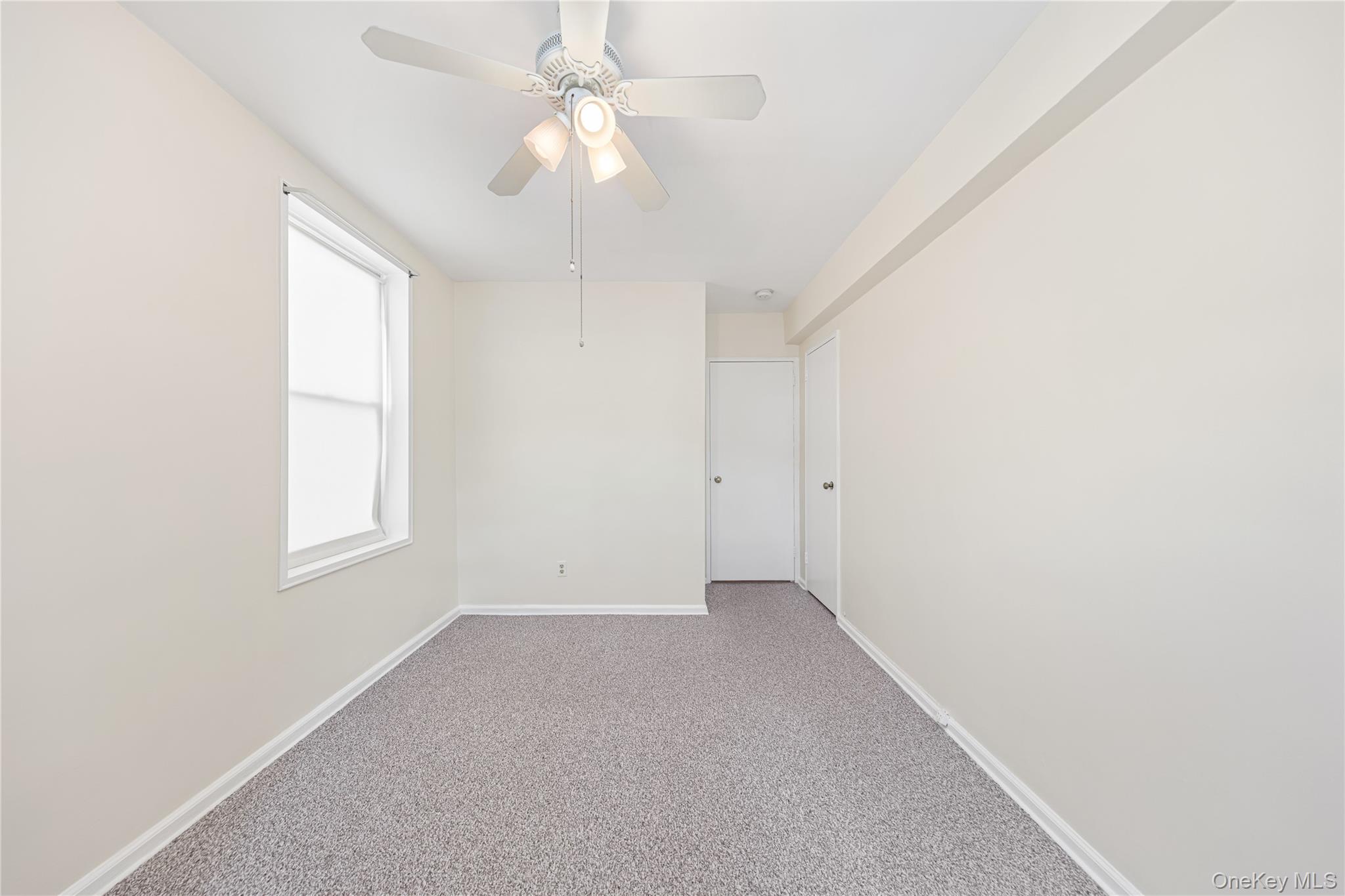126 Church Street, Unit 2D New Rochelle, NY 10805 - Photo 10 of 32 an empty room with chandelier fan and windows