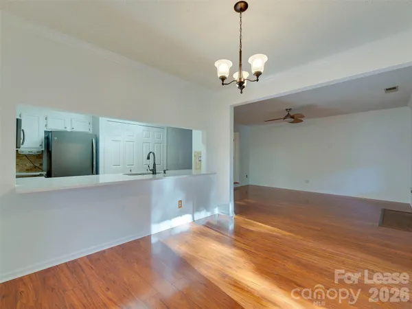 a view of a room with a chandelier and wooden floor