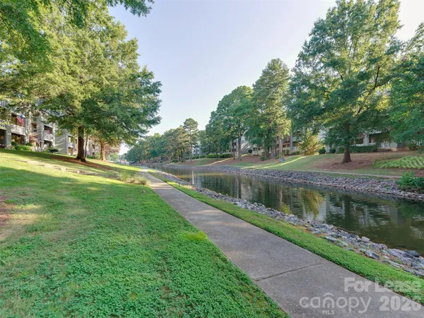 a view of a lake with a big yard and large trees