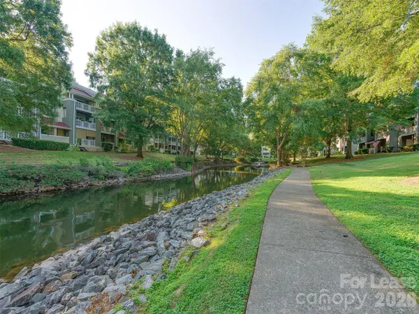 a view of a lake with a big yard and large trees