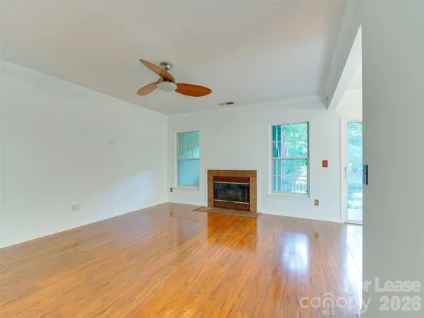 an empty room with windows fireplace and wooden floor