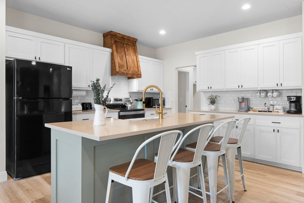 Elegant quartz countertops and a statement wood hood vent elevate this bright workspace.
