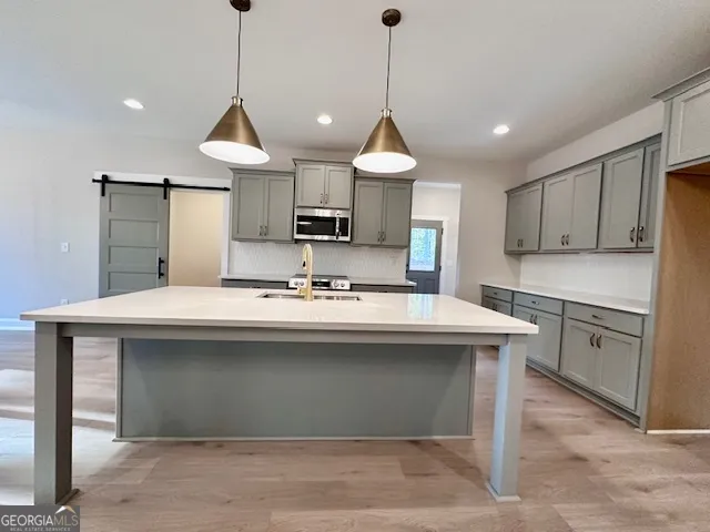 a kitchen with kitchen island stainless steel appliances a sink a stove a refrigerator and cabinets