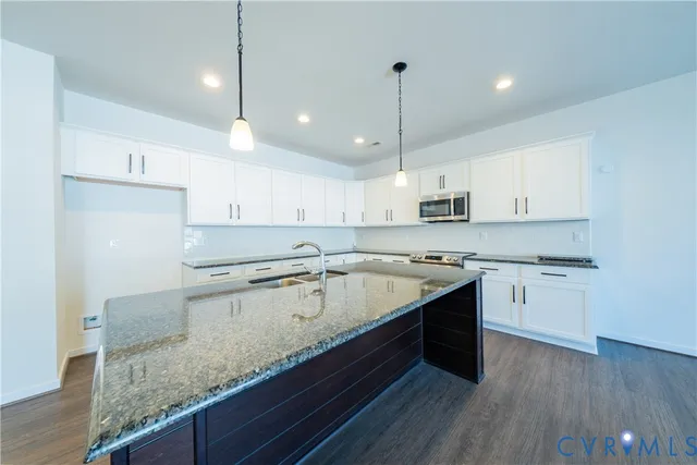 a kitchen with stainless steel appliances granite countertop a stove and a wooden floor