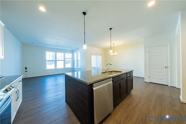 a kitchen with stainless steel appliances granite countertop a sink a stove and a wooden floors
