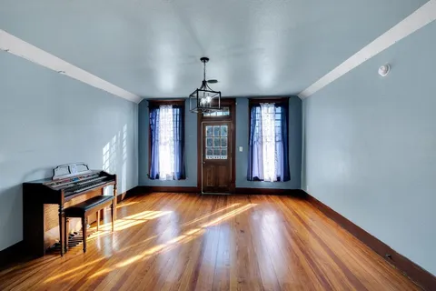 a view of an empty room with window and wooden floor
