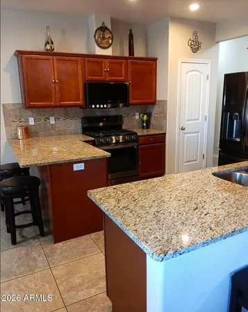 a kitchen with stainless steel appliances granite countertop a refrigerator and a wooden cabinets