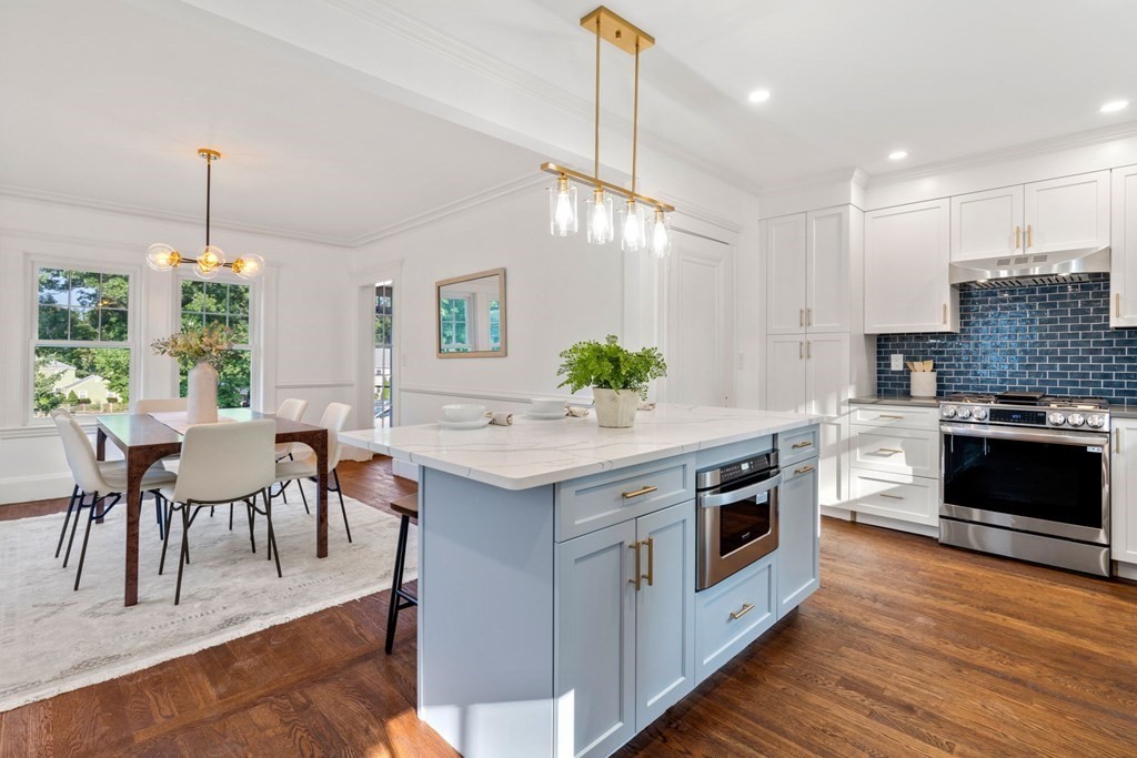 a kitchen with stainless steel appliances granite countertop a stove a sink a oven a dining table and chairs