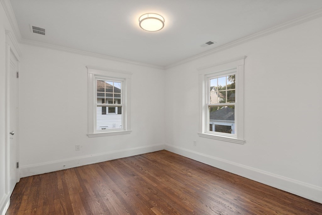 4 Clement Avenue Boston, MA 02132 - Photo 22 of 39 an empty room with wooden floor and windows