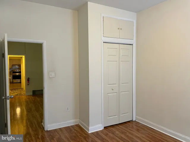 an empty room with wooden floor cabinet and door